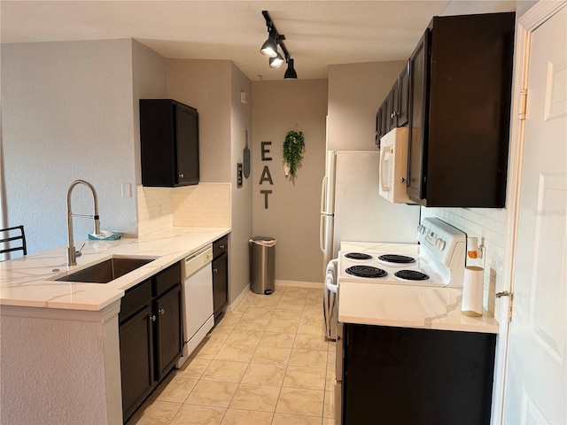 kitchen with sink, backsplash, light tile patterned floors, light stone countertops, and white appliances