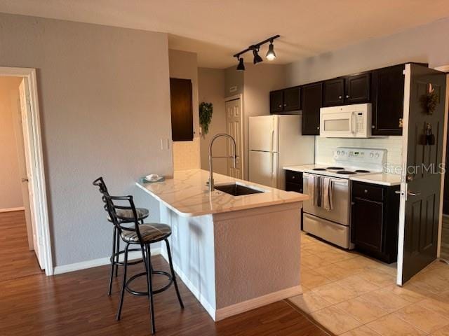 kitchen featuring sink, a kitchen breakfast bar, kitchen peninsula, white appliances, and light hardwood / wood-style flooring