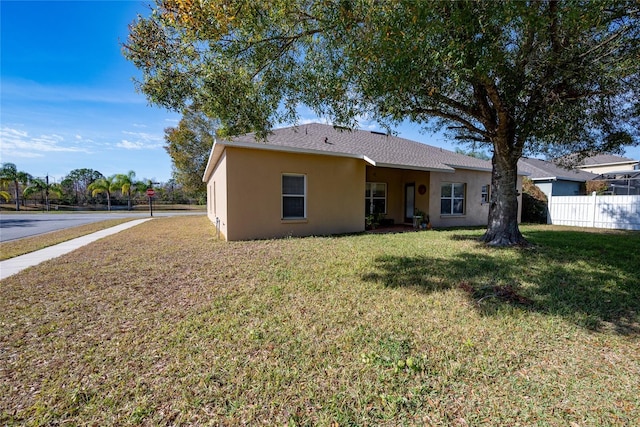 view of front of home with a front yard, fence, and stucco siding