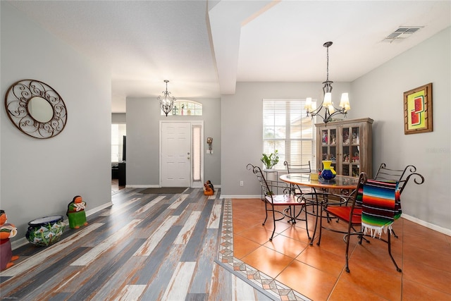 dining area featuring a chandelier, tile patterned flooring, visible vents, and baseboards