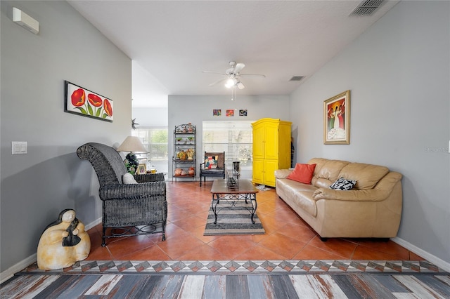 living area with light tile patterned floors, a ceiling fan, visible vents, and baseboards