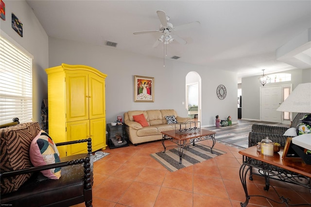 living area with light tile patterned floors, ceiling fan, visible vents, and arched walkways