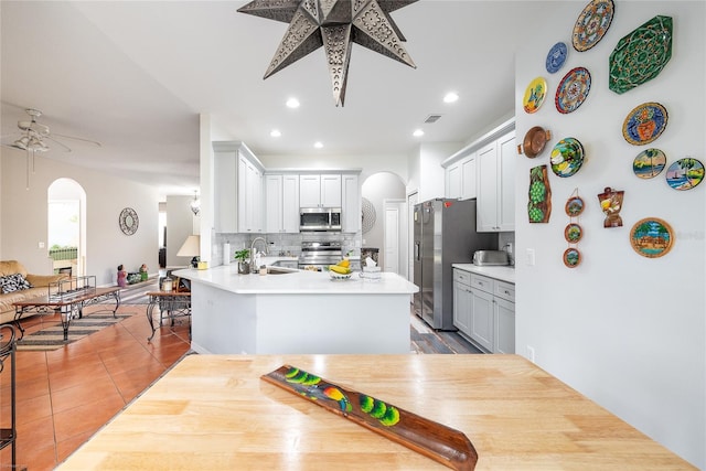 kitchen featuring sink, kitchen peninsula, stainless steel appliances, decorative backsplash, and white cabinets