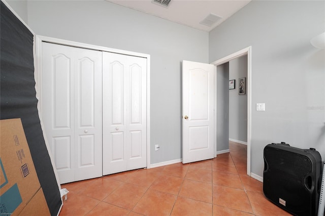 bedroom featuring light tile patterned floors, a closet, visible vents, and baseboards