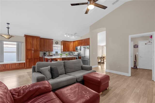 living room with ceiling fan, high vaulted ceiling, a wealth of natural light, and light wood-type flooring