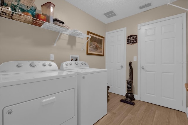 laundry room with washing machine and clothes dryer, light hardwood / wood-style floors, and a textured ceiling