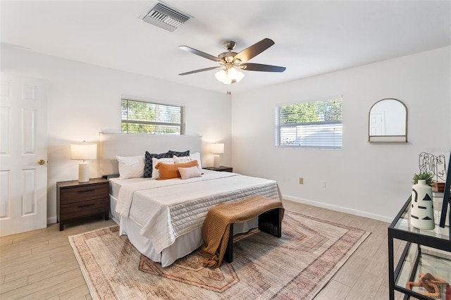 bedroom with ceiling fan, light hardwood / wood-style floors, and multiple windows