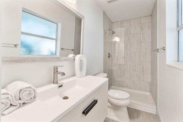 bathroom featuring vanity, a tile shower, and toilet