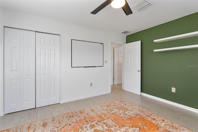 unfurnished bedroom with ornamental molding, hardwood / wood-style floors, ceiling fan, and a closet