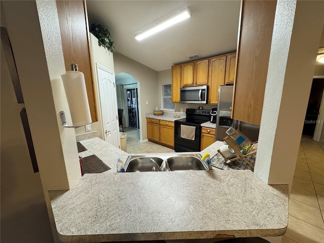 kitchen featuring sink, light tile patterned flooring, kitchen peninsula, and appliances with stainless steel finishes