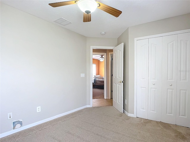 unfurnished bedroom with light colored carpet, a closet, and ceiling fan