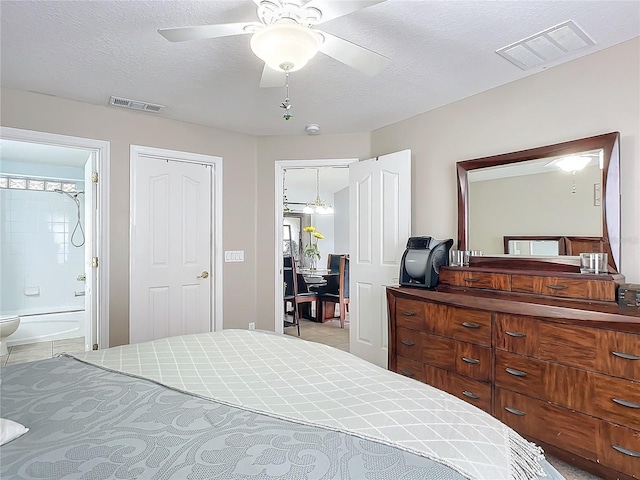 tiled bedroom featuring ceiling fan, a textured ceiling, and ensuite bath