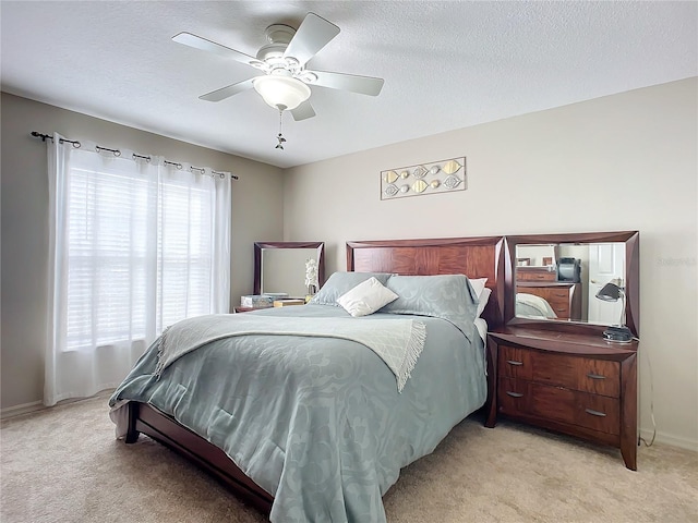 bedroom with ceiling fan, light carpet, and a textured ceiling