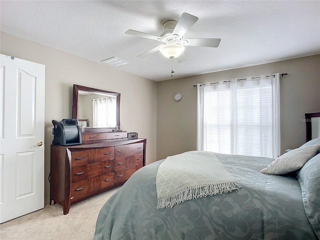 carpeted bedroom featuring multiple windows, ceiling fan, and a textured ceiling