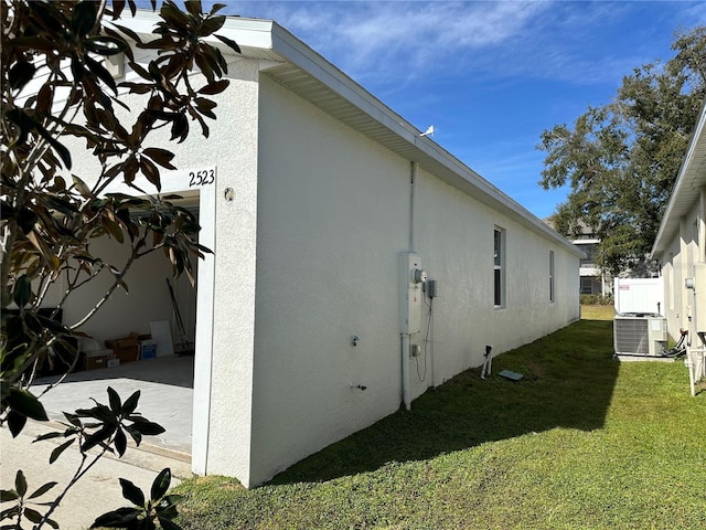 view of side of property with central AC unit and a yard