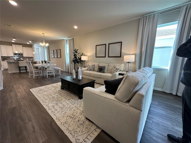 living room with dark wood-type flooring and a notable chandelier