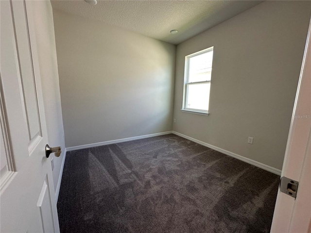 spare room with dark carpet and a textured ceiling