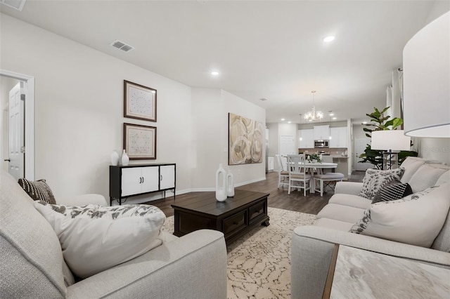 living area with wood finished floors, visible vents, baseboards, recessed lighting, and a notable chandelier