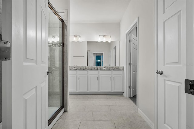 full bathroom featuring double vanity, a stall shower, tile patterned floors, and a sink