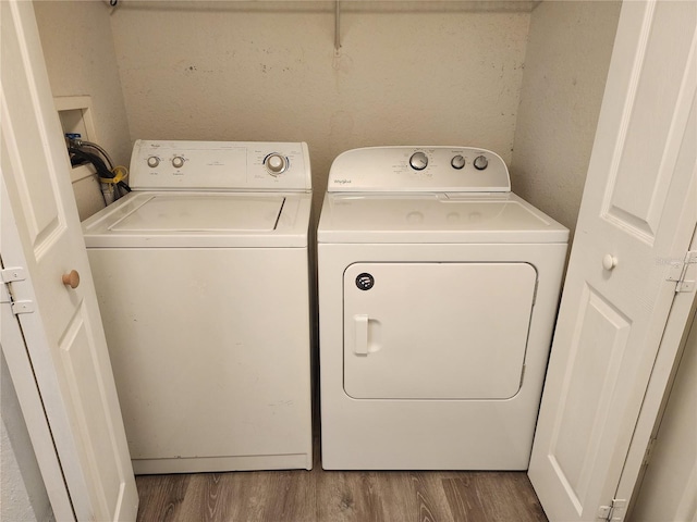 clothes washing area featuring laundry area, dark wood finished floors, and washing machine and clothes dryer