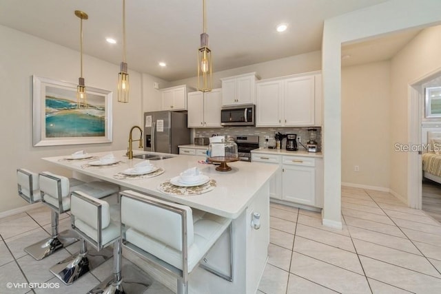 kitchen featuring white cabinetry, decorative light fixtures, a kitchen island with sink, and stainless steel appliances