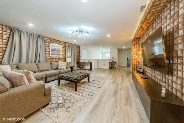 living room with a textured ceiling, brick wall, and light wood-type flooring