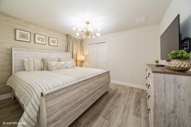 bedroom with an inviting chandelier, light wood-type flooring, and a closet