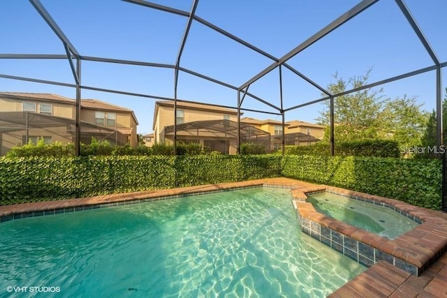 view of pool with an in ground hot tub and glass enclosure