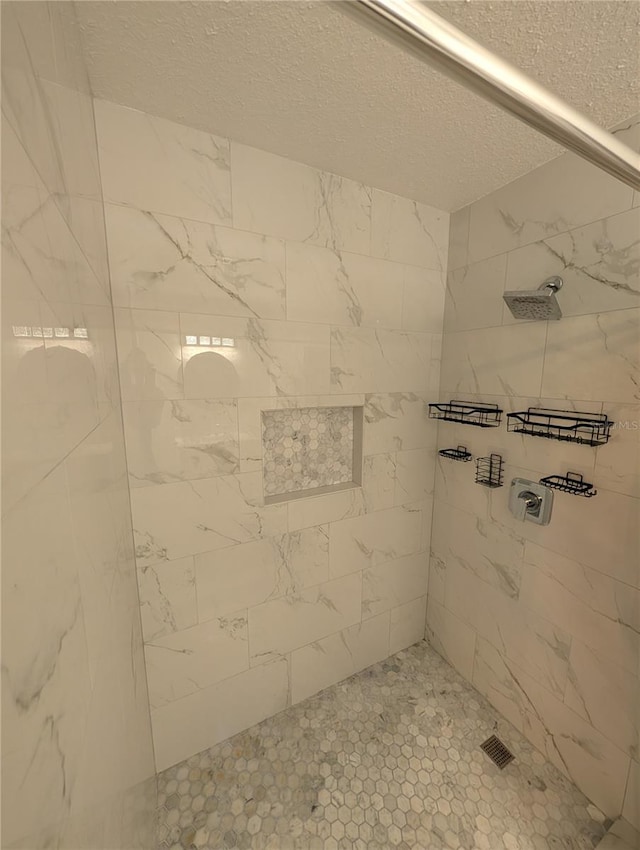 bathroom featuring a textured ceiling and tiled shower