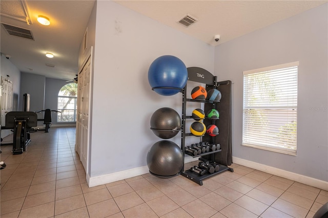 exercise area with ceiling fan and light tile patterned floors