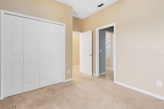 unfurnished bedroom featuring light carpet and a closet