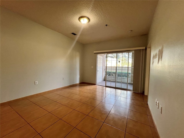 unfurnished room with tile patterned flooring and a textured ceiling