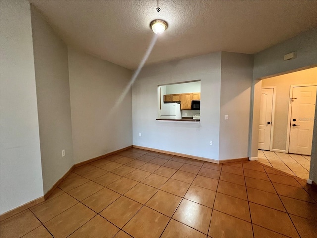 spare room with a textured ceiling and light tile patterned floors