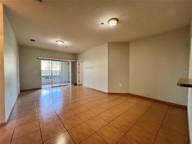 tiled empty room featuring a textured ceiling