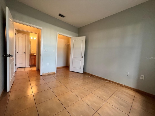 unfurnished bedroom featuring light tile patterned floors, a walk in closet, and a closet