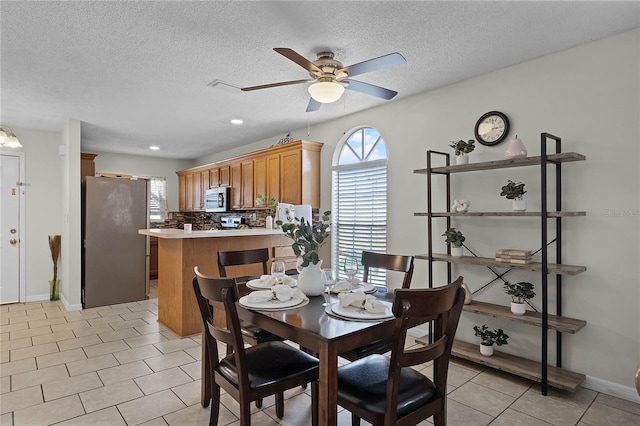 tiled dining space featuring a textured ceiling and ceiling fan