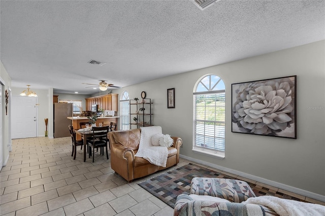 tiled living room with ceiling fan and a textured ceiling