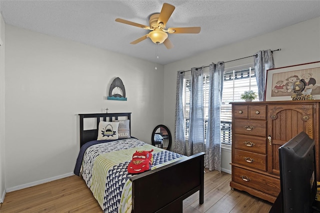 bedroom with ceiling fan, a textured ceiling, and light hardwood / wood-style floors