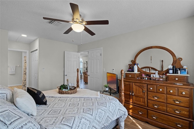 bedroom featuring ceiling fan, light hardwood / wood-style flooring, a closet, and a textured ceiling