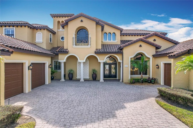 mediterranean / spanish house with a garage and french doors