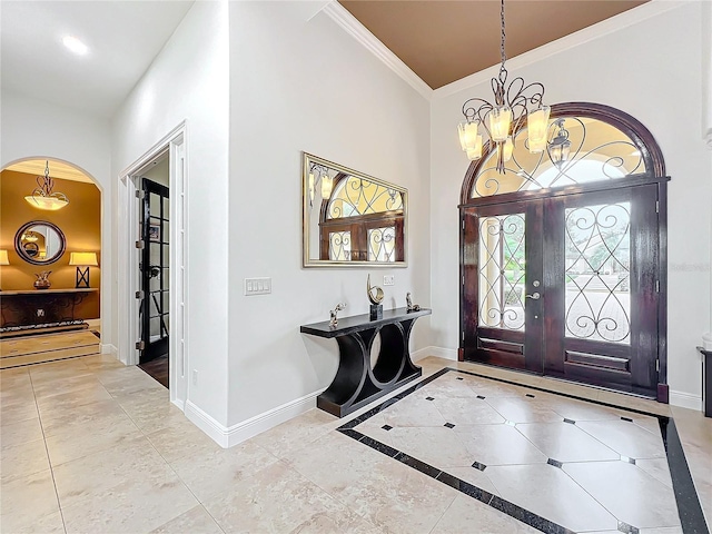 foyer with crown molding, an inviting chandelier, and french doors