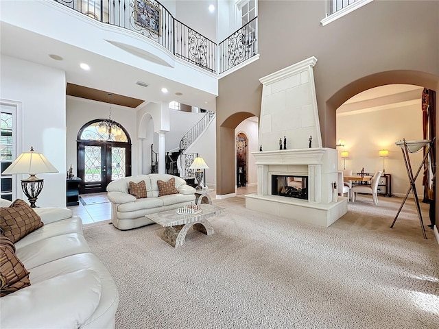 living room with a towering ceiling, light carpet, and french doors