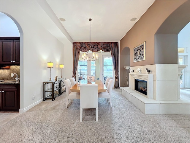 dining room with sink, light colored carpet, and a chandelier