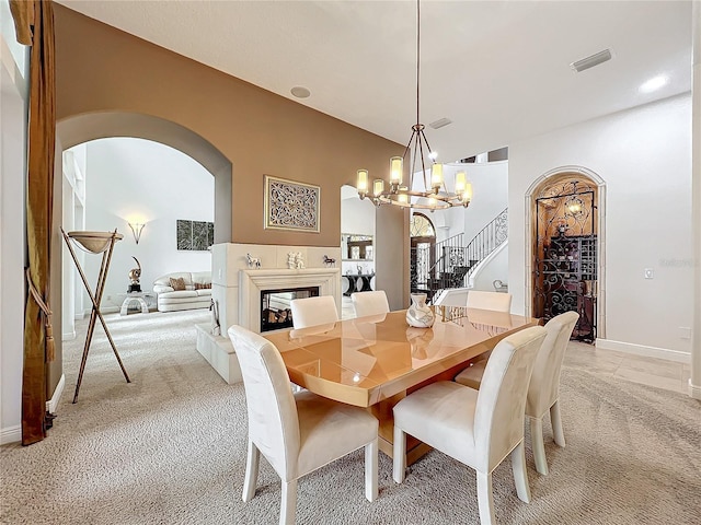 dining space with light carpet, a notable chandelier, and a multi sided fireplace