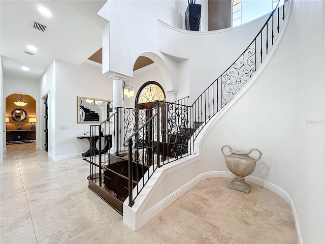 staircase with a towering ceiling and ornate columns