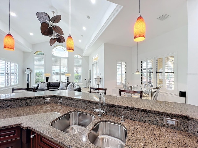 kitchen with ceiling fan, light stone countertops, sink, and hanging light fixtures