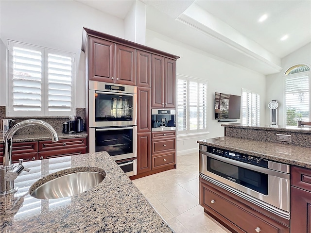 kitchen featuring light stone countertops, sink, light tile patterned floors, and double oven