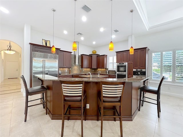 kitchen featuring backsplash, a large island, hanging light fixtures, and dark stone countertops