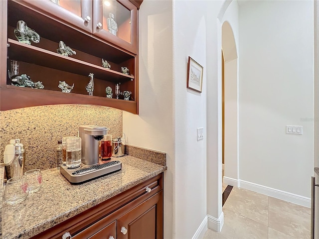 bar featuring backsplash, light stone countertops, and light tile patterned floors