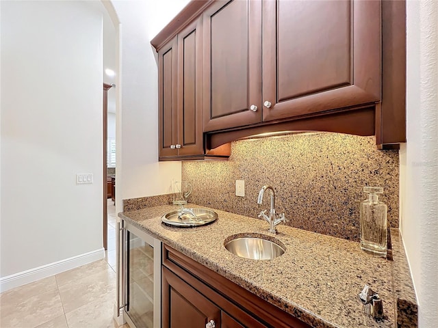 kitchen with wine cooler, sink, light stone counters, light tile patterned floors, and backsplash